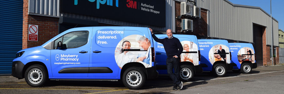 Business owner proudly stood with new vinyl graphics on a fleet of company vans