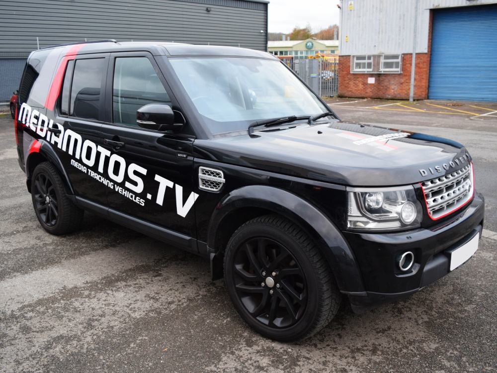 Black company Land Rover Discovery with branded vinyl graphics.