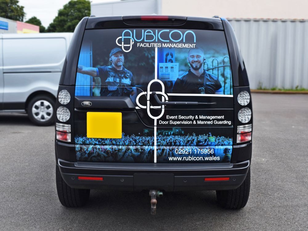 Rear of company Land Rover Discovery with branded partial vehicle wrap.