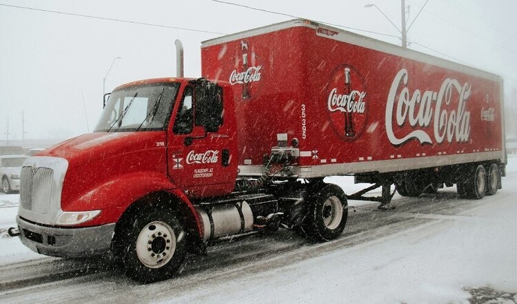 Coca-Cola livery on a red truck driving through the snow.