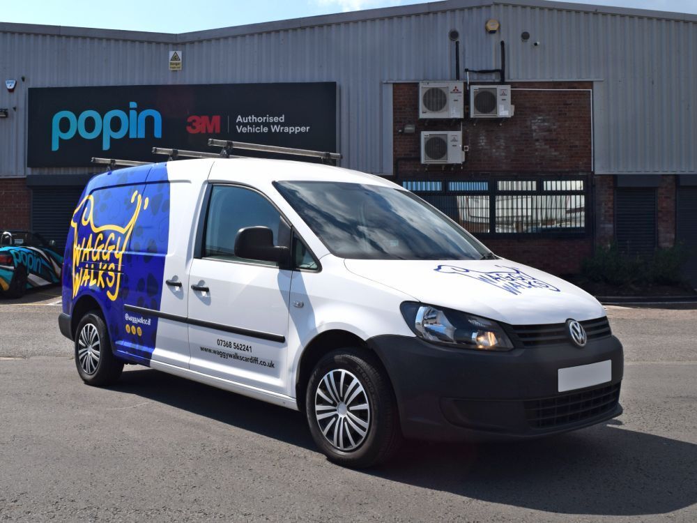 White company Volkswagen Caddy Maxi with branded partial van wrap and vinyl graphics outside Popin in Cardiff.