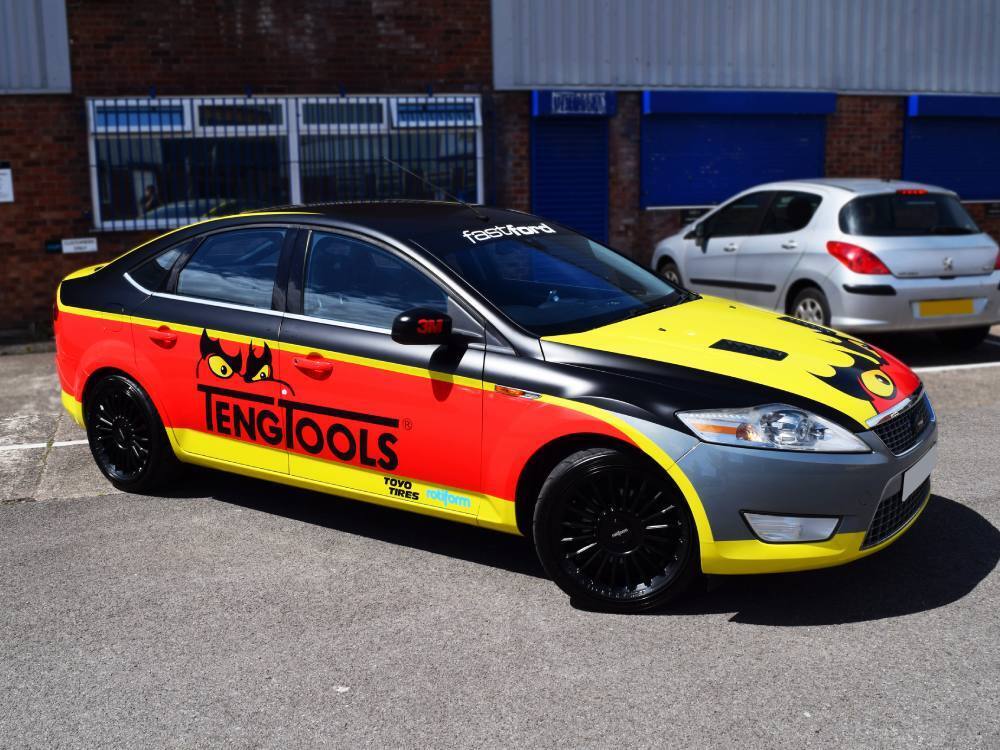 Bright red and yellow commercial wrap on Ford Mondeo company car.