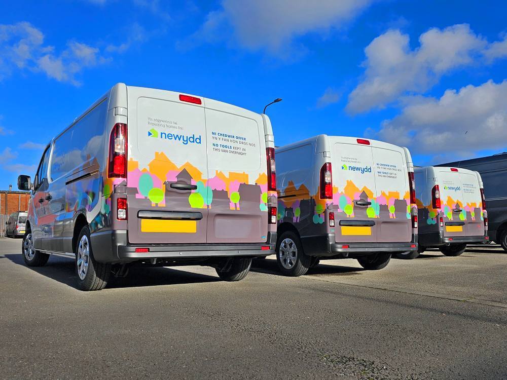 Fleet of Renault Trafic vans with matching company vehicle wraps and graphics on rear end.