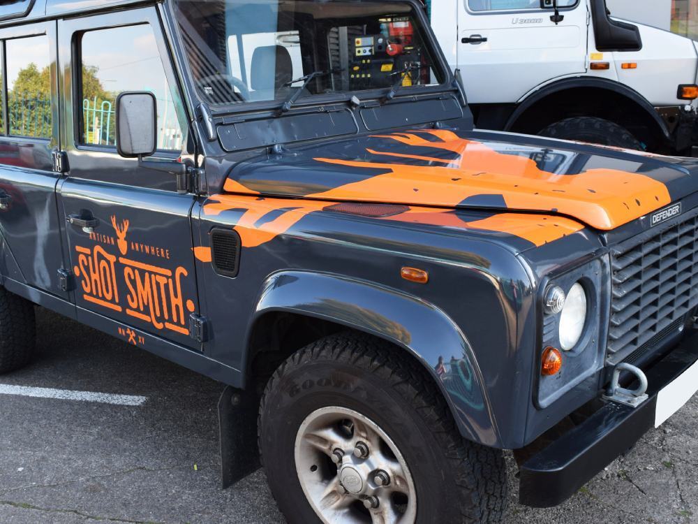 O0range branded vinyl graphics installed on company Land Rover Defender.