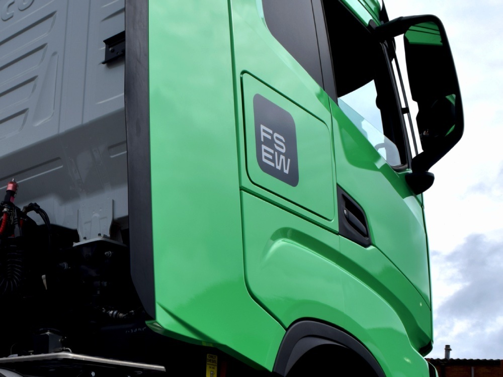 Green livery and branded company vehicle graphics on an Iveco lorry.