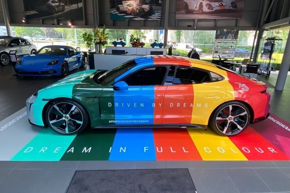 Porsche Taycan Turbo with bespoke colourful motorsport wrap parked inside showroom in Cardiff.