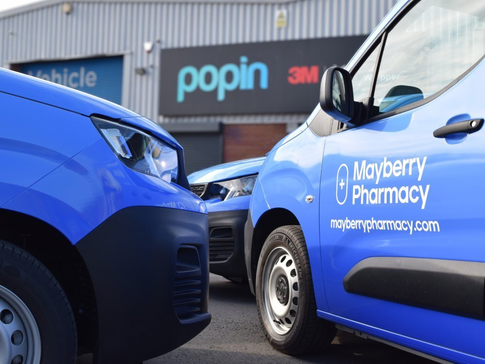 Branded company vinyl graphics on door of Peugeot Partner van fleet.