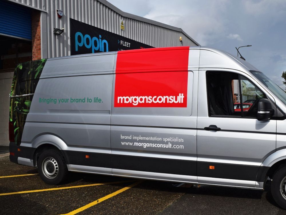 Silver Volkswagen Crafter company van with partial branded wrap outside Popin in Cardiff.