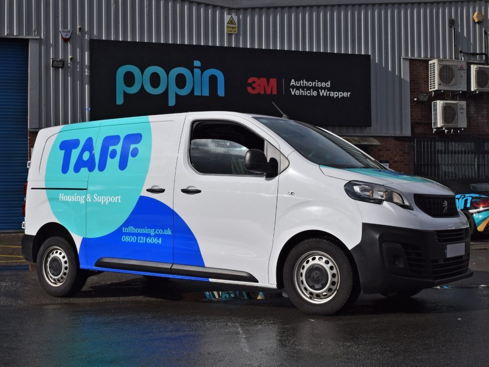 Branded blue partial vehicle wrap on white Peugeot Expert company van.