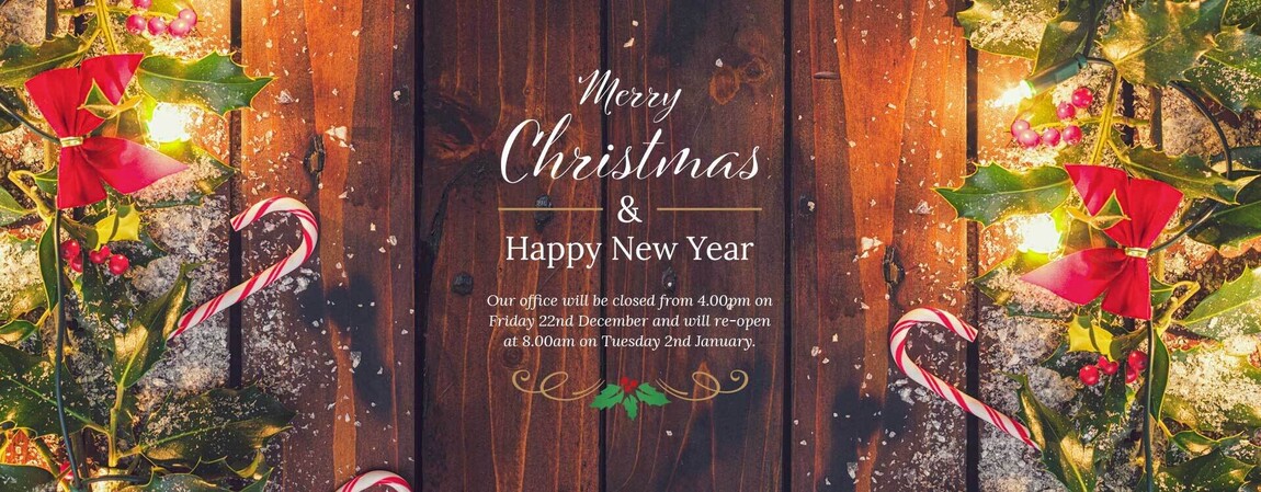 An example banner image of a cosy christmas scene showing a wooden door framed with christmas decorations with a merry christmas message in the middle, wishing a merry christmas and a happy new year.