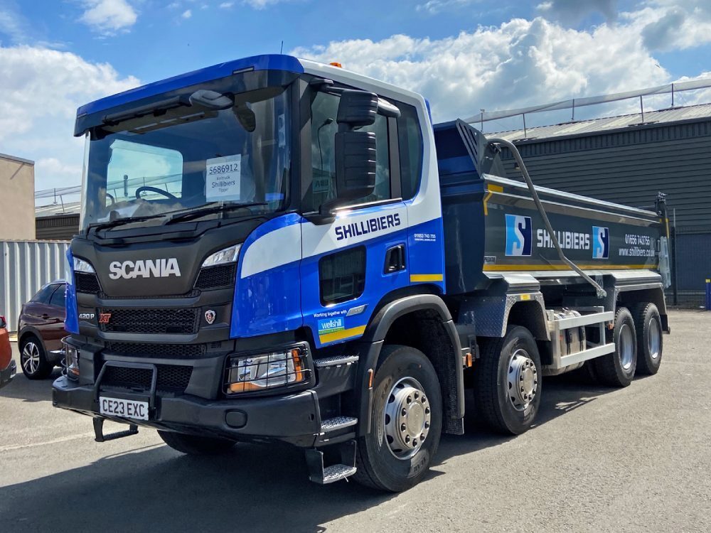 Blue vehicle wrap and branded vinyl graphics on a Scania truck.