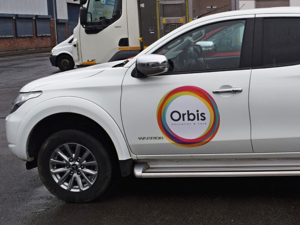 Branded vinyl graphics on door of white company Mitsubishi L200.