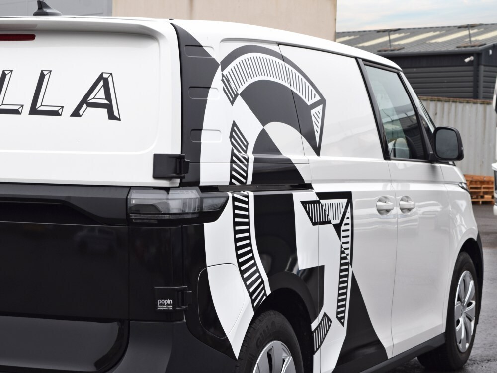 Electric Volkswagen ID. Buzz with company branded black and white van livery.