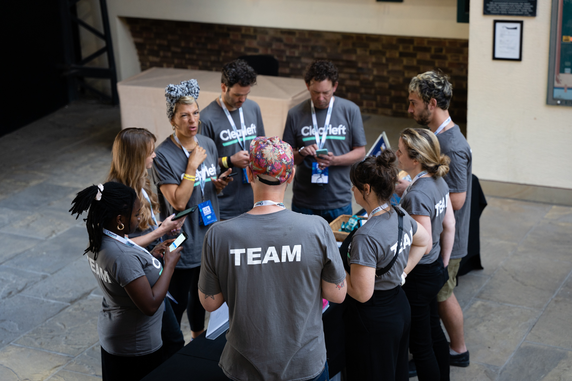A group of people wearing Clearleft-branded T-shirts gathered in a huddle.
