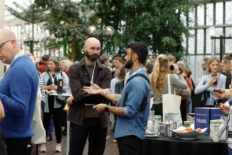Conference attendees networking and chatting in a large plant-filled venue during a break at Leading Design London.