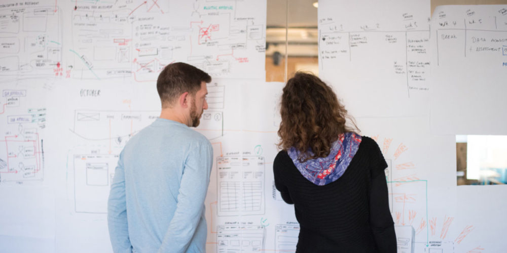 Katie and client stand in front of a huge sketched out service system