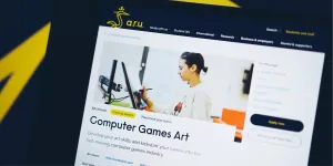 A shallow focus photo of the ARU course page design on a computer screen. Only the top part of the page is shown. The image is shot from a quirky angle and abstract brand elements can be seen in the background.