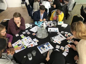 Group of engaged workshop participants around a table scattered with images of UI components.