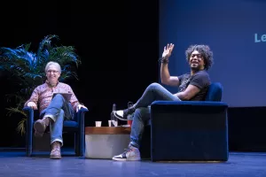 Jeremy and Dan on stage together, sitting in comfy chairs, smiling and having fun.