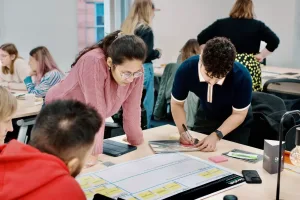 A2-sized paper showing a grid, is laid on a table, surrounded by workshop attendees studying it.