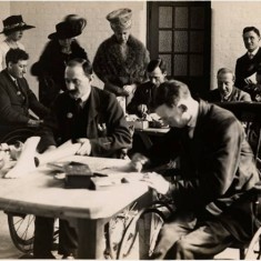 Queen Mary and Princess Mary with ex-servicemen in wheelchairs at work in a workshop manufacturing artificial limbs, 5 Jun 1919.  | Hammersmith and Fulham Archives