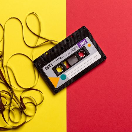 Black cassette tape on top of red and yellow surface 1626481