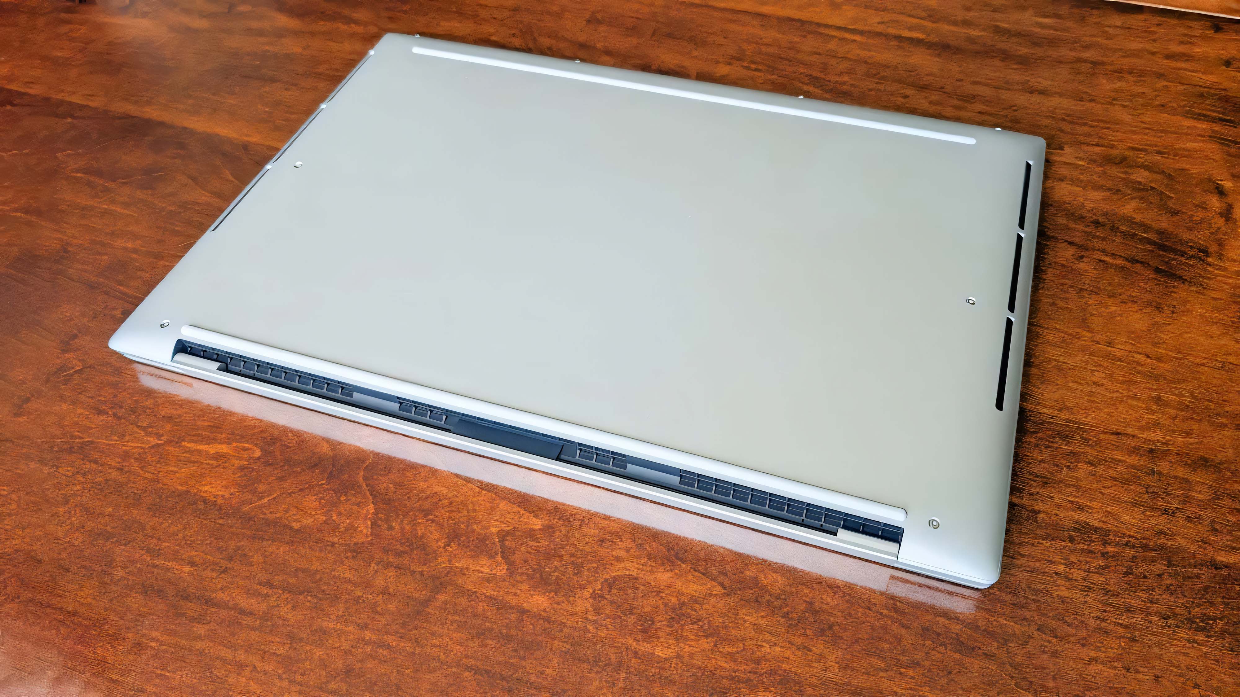 Нижняя часть Dell 16 Premium на деревянном столе.