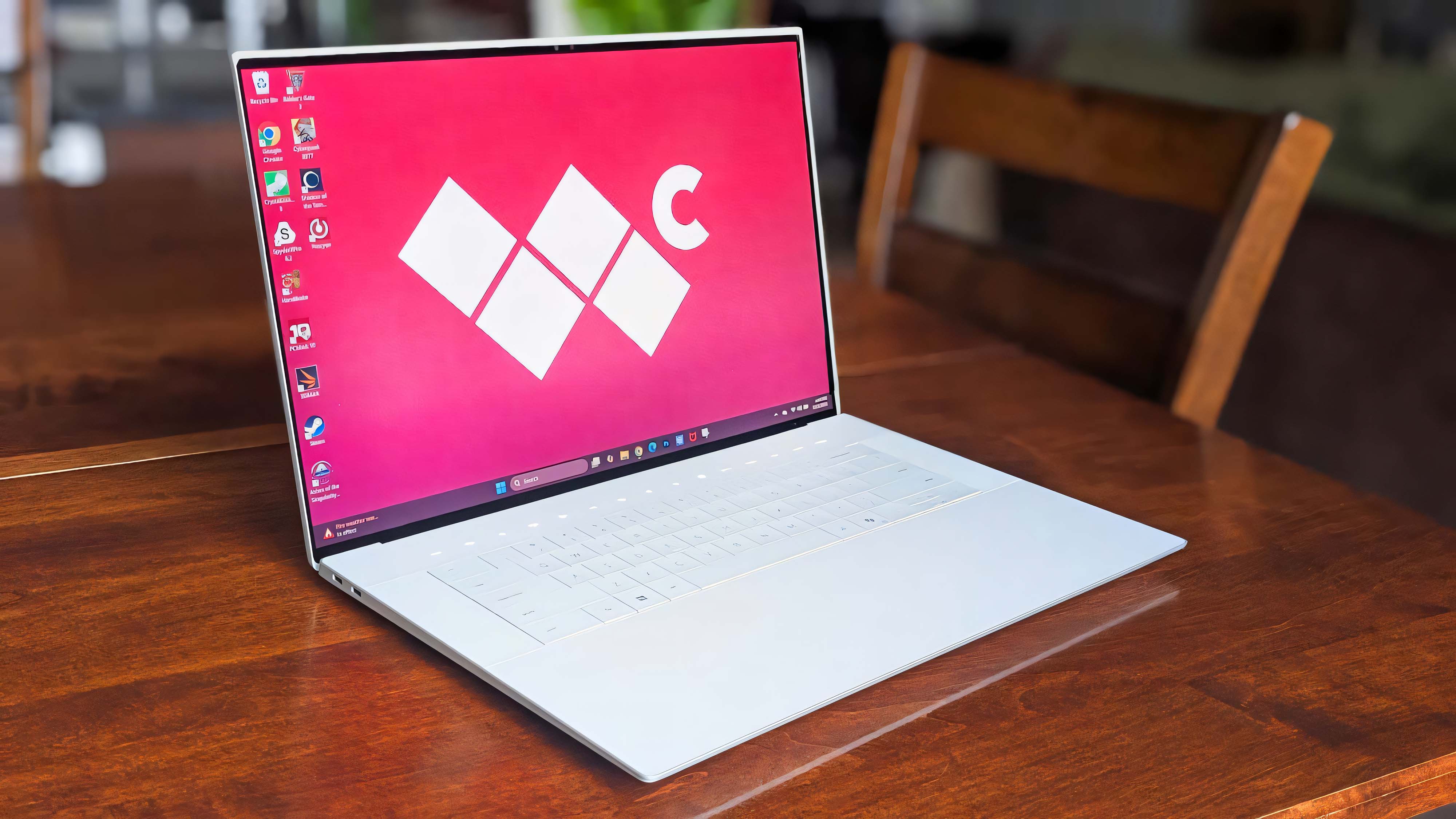Ноутбук Dell 16 Premium стоит на деревянном столе. Логотип Windows Central отображается в качестве фона.