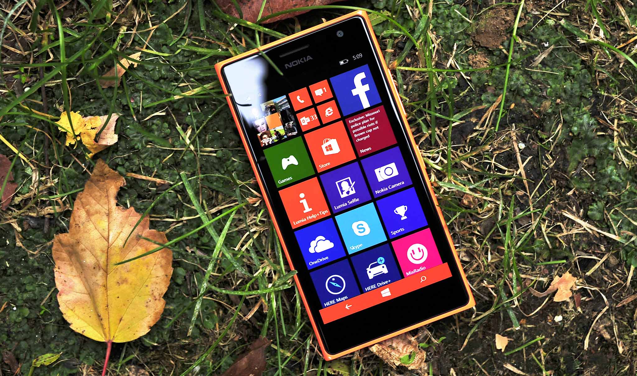 Nokia Lumia 735 оранжевого цвета на траве с осенними листьями