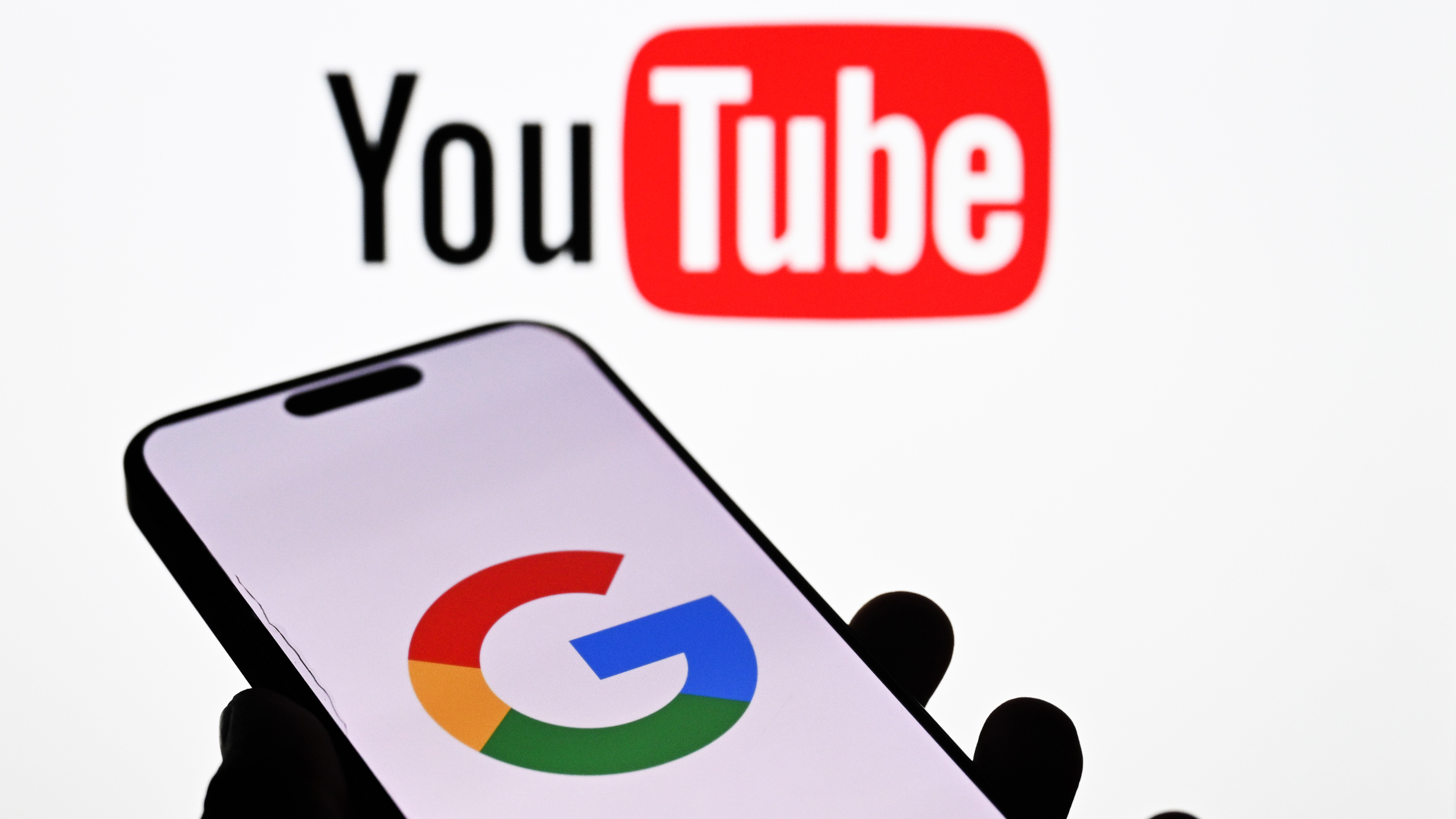 Логотипы Google и YouTube на экране мобильного телефона и компьютера.