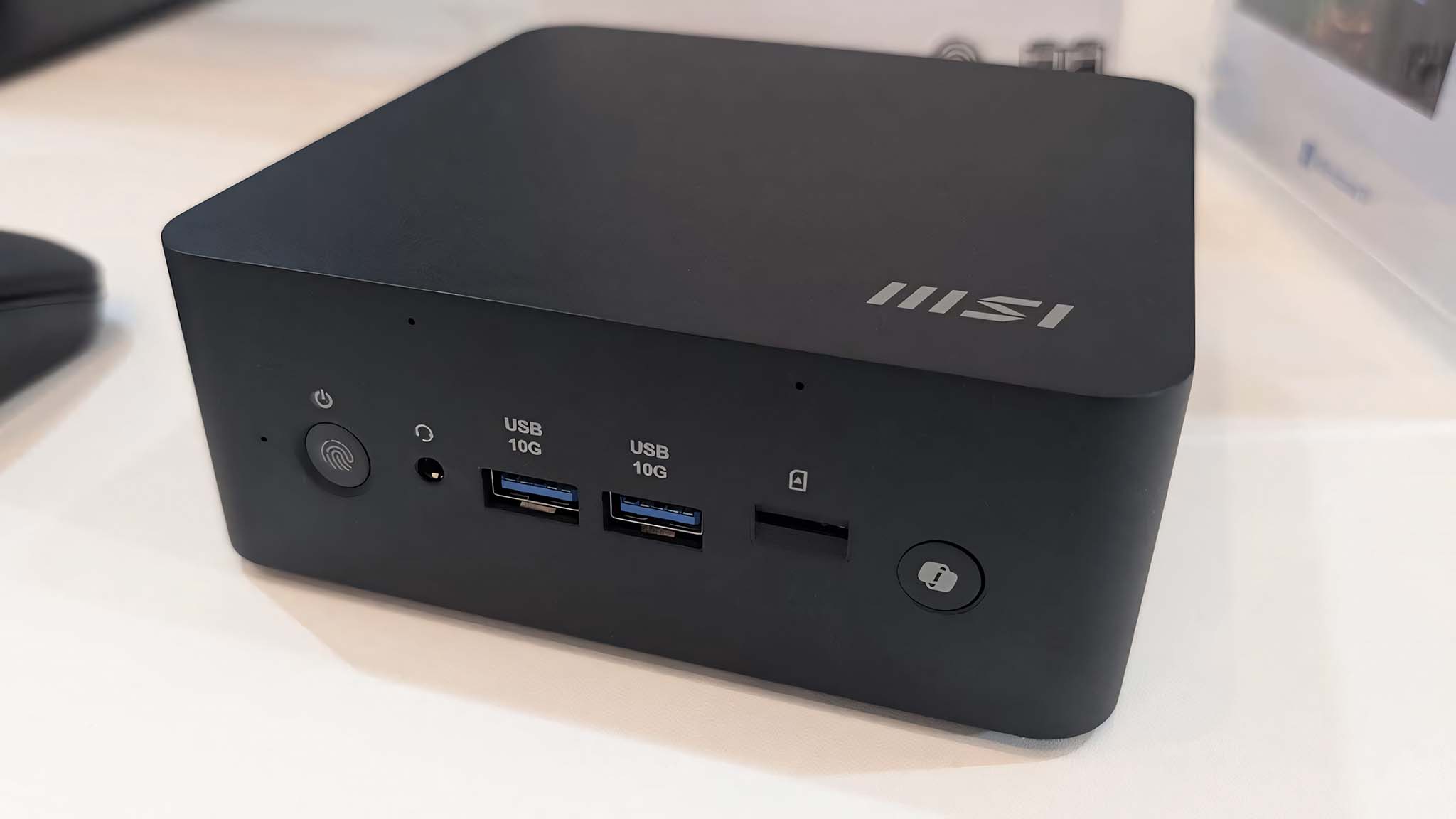 Передняя сторона MSI Cubi NUC AI+ 2M на белом столе.