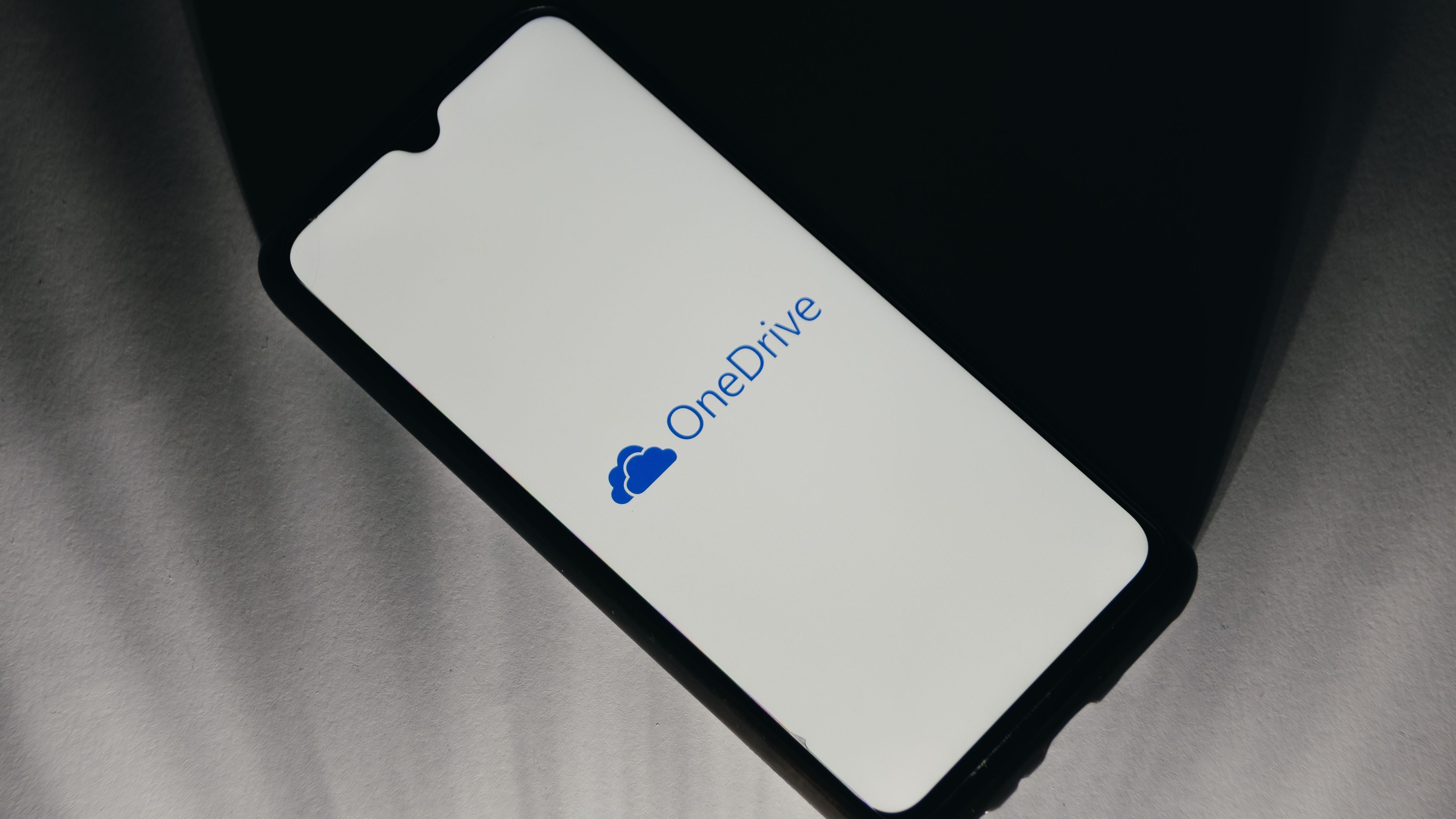 OneDrive logo is displayed on a smartphone screen.