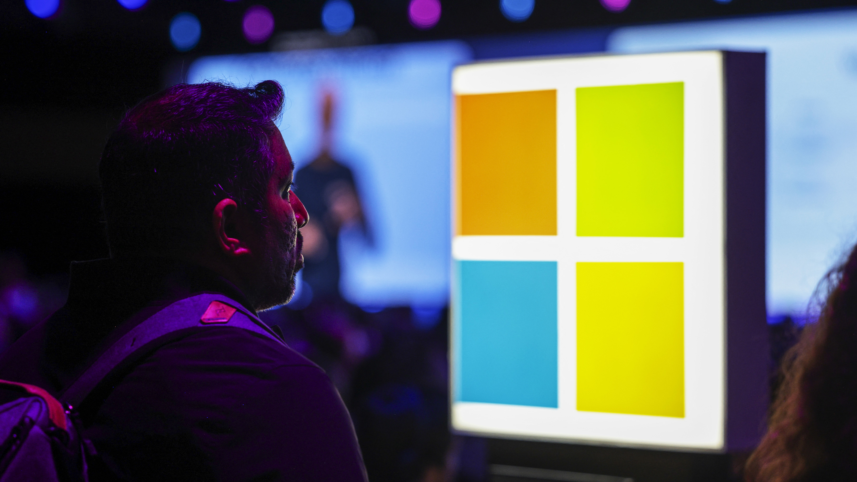 An audience member seated near a Microsoft logo listens as Microsoft Chairman and Chief Executive Officer Satya Nadella speaks during the Microsoft Build conference opening keynote in Seattle, Washington on May 19, 2025. (Photo by Jason Redmond / AFP) (Photo by JASON REDMOND/AFP via Getty Images)