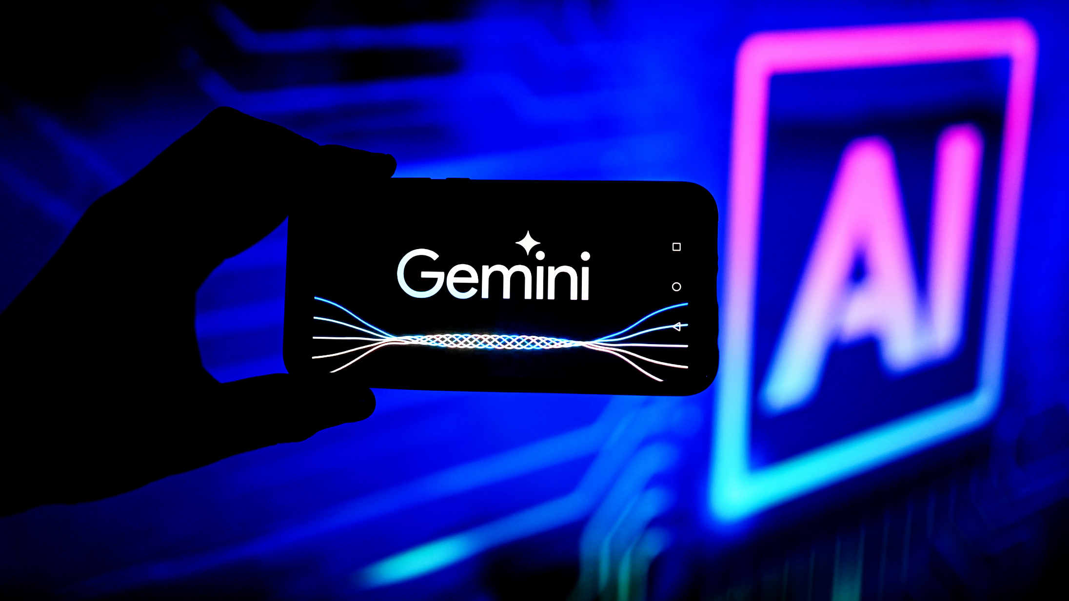 Логотип Google Gemini AI на экране телефона, лежащего на ноутбуке.