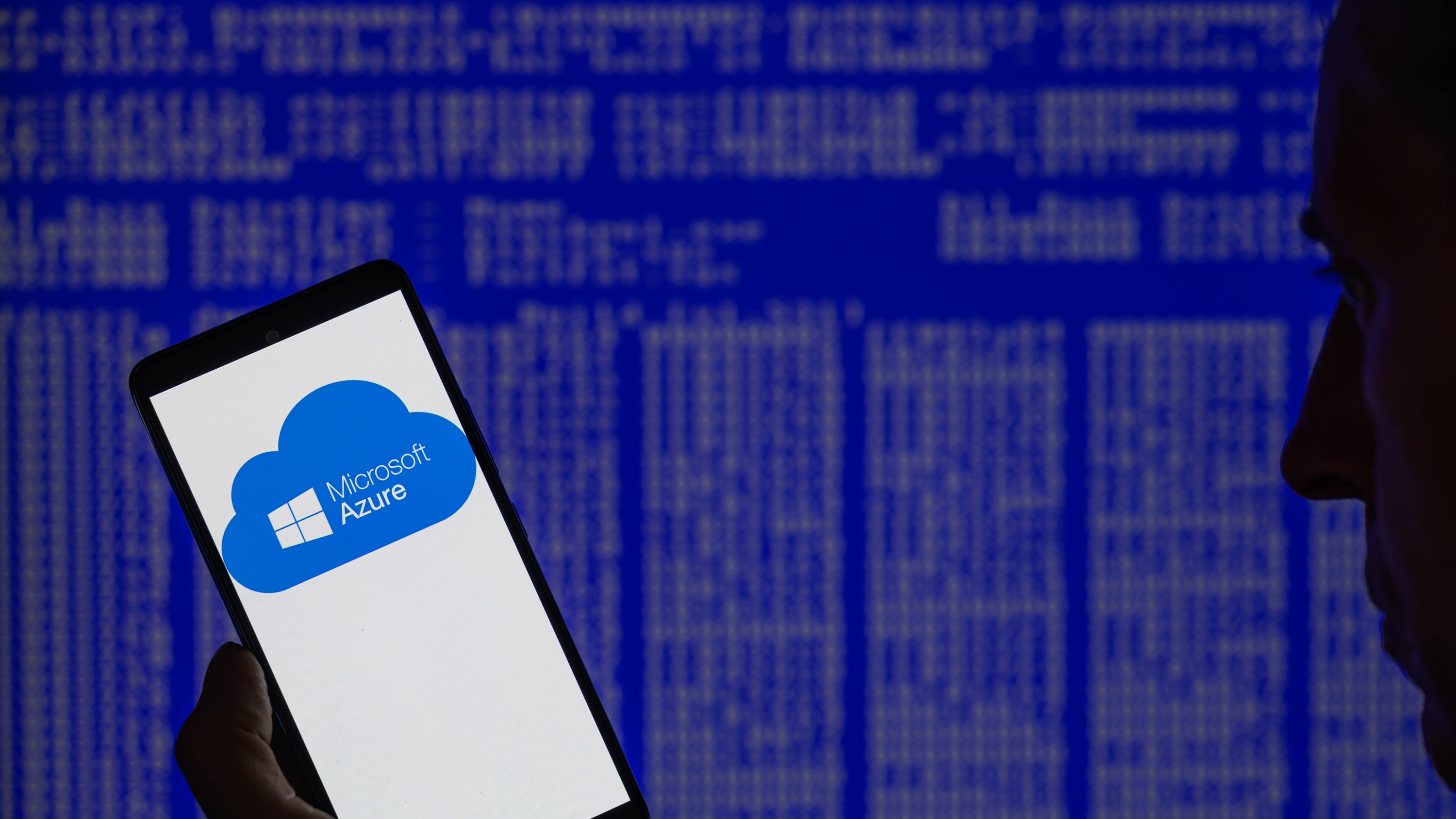Microsoft Azure отображается на смартфоне с синим экраном Windows на заднем плане.