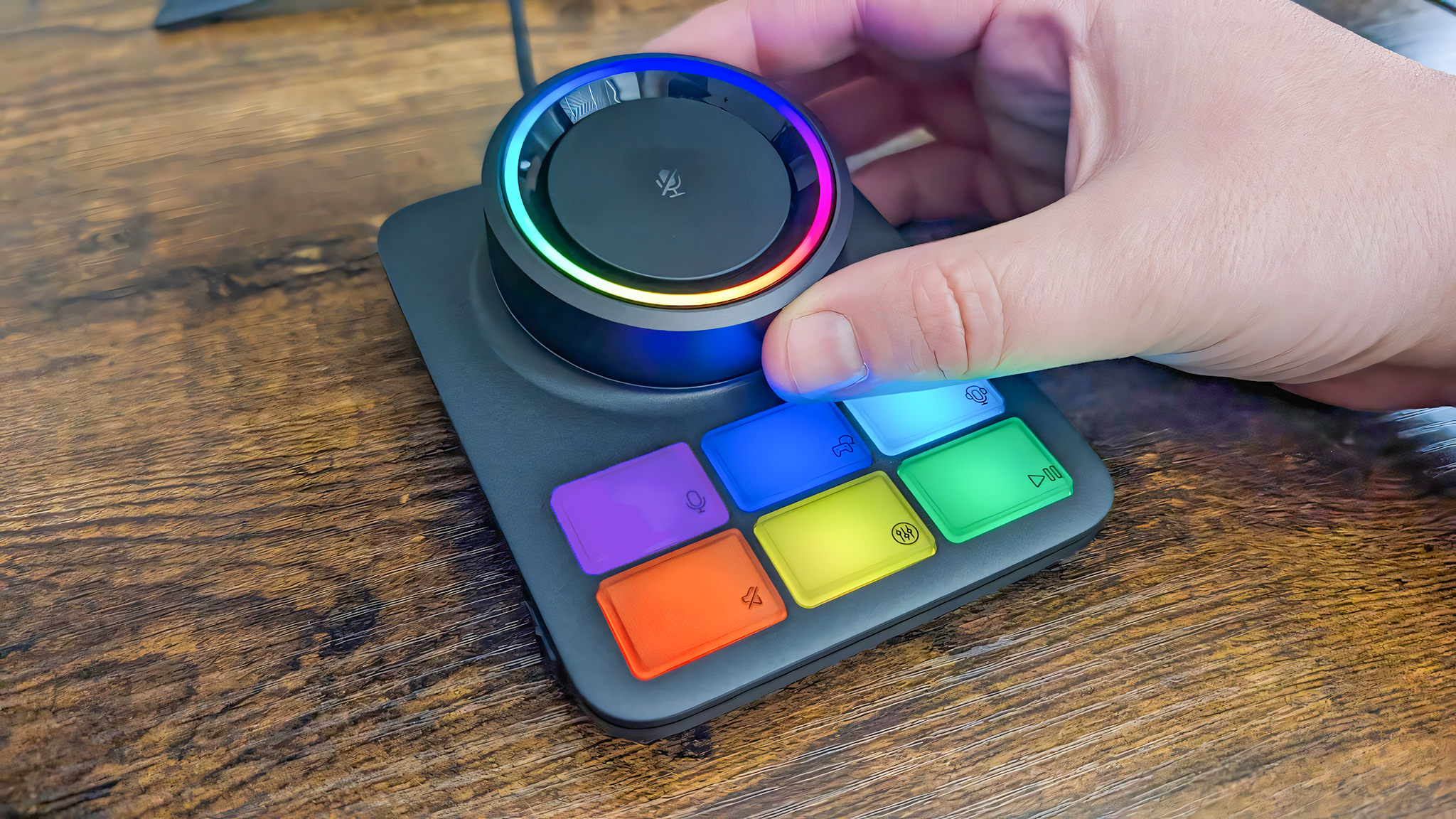 Крупный план RGB Base Station с подсветкой. Рука вращает большой регулятор громкости.