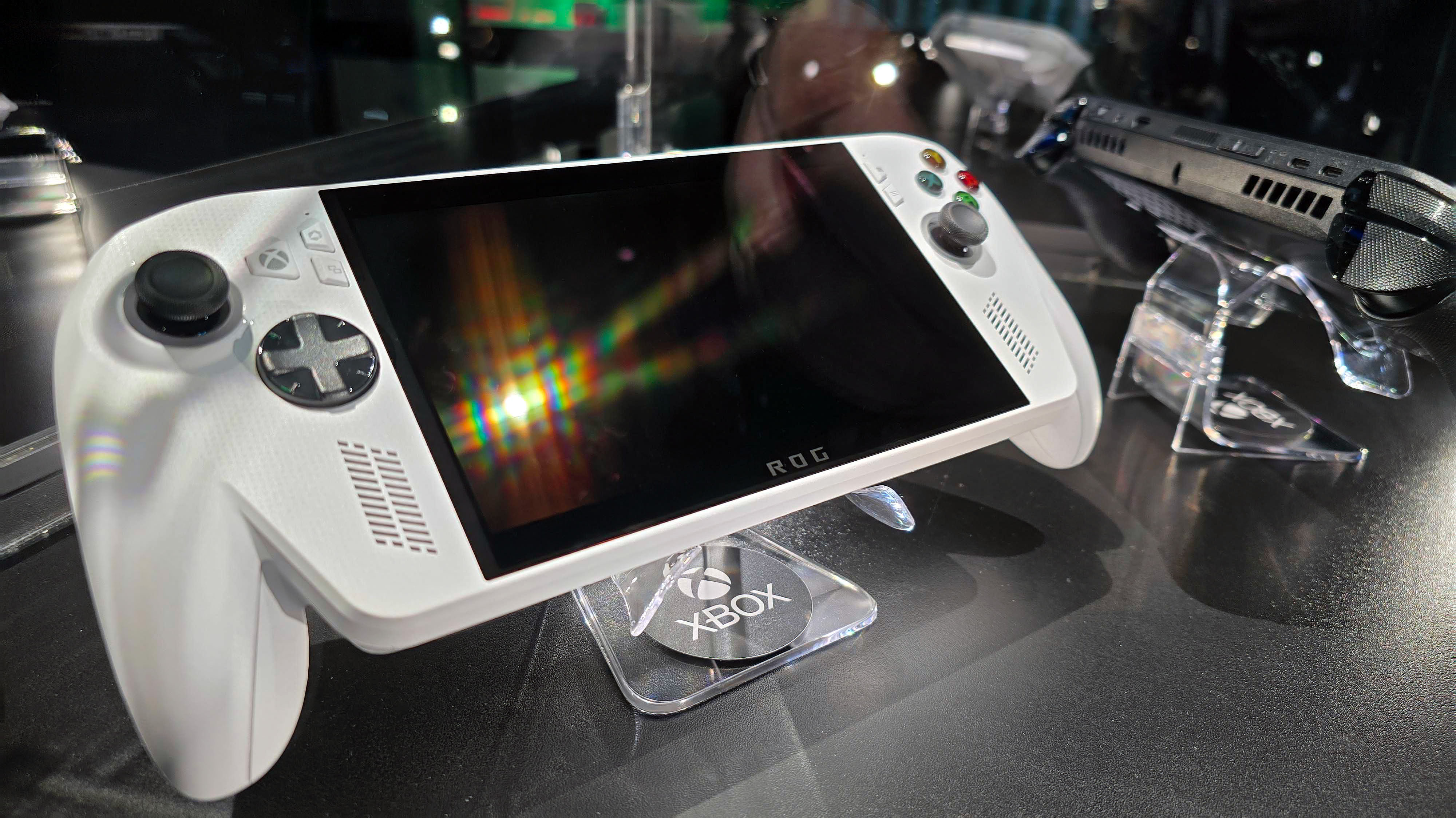 ASUS ROG Xbox Ally (white) and ROG Xbox Ally X (black) in a glass display case at Gamescom in August, 2025.