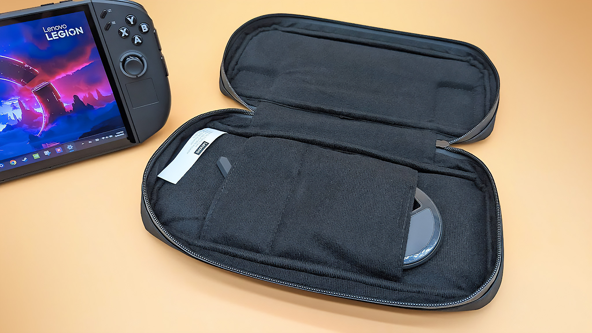 Чехол Lenovo Legion Go 2 лежит открытым с док-станцией контроллера в режиме FPS и аксессуаром для крышки контактов контроллера, торчащим из некоторых карманов.