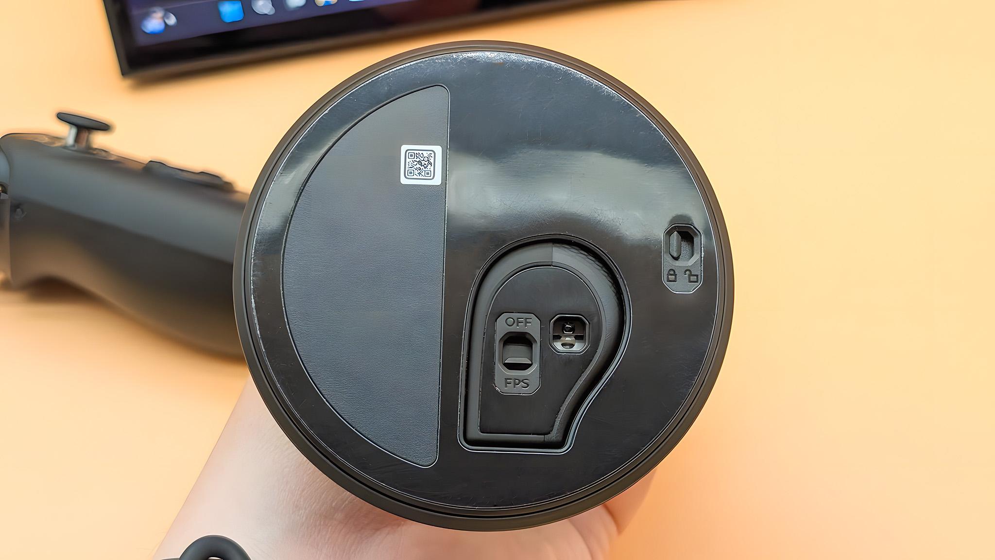 Нижняя сторона базы режима FPS с правым контроллером Lenovo Legion Go 2, зафиксированным в нем. Есть переключатель для освобождения контроллера и другой переключатель для включения и выключения режима FPS.