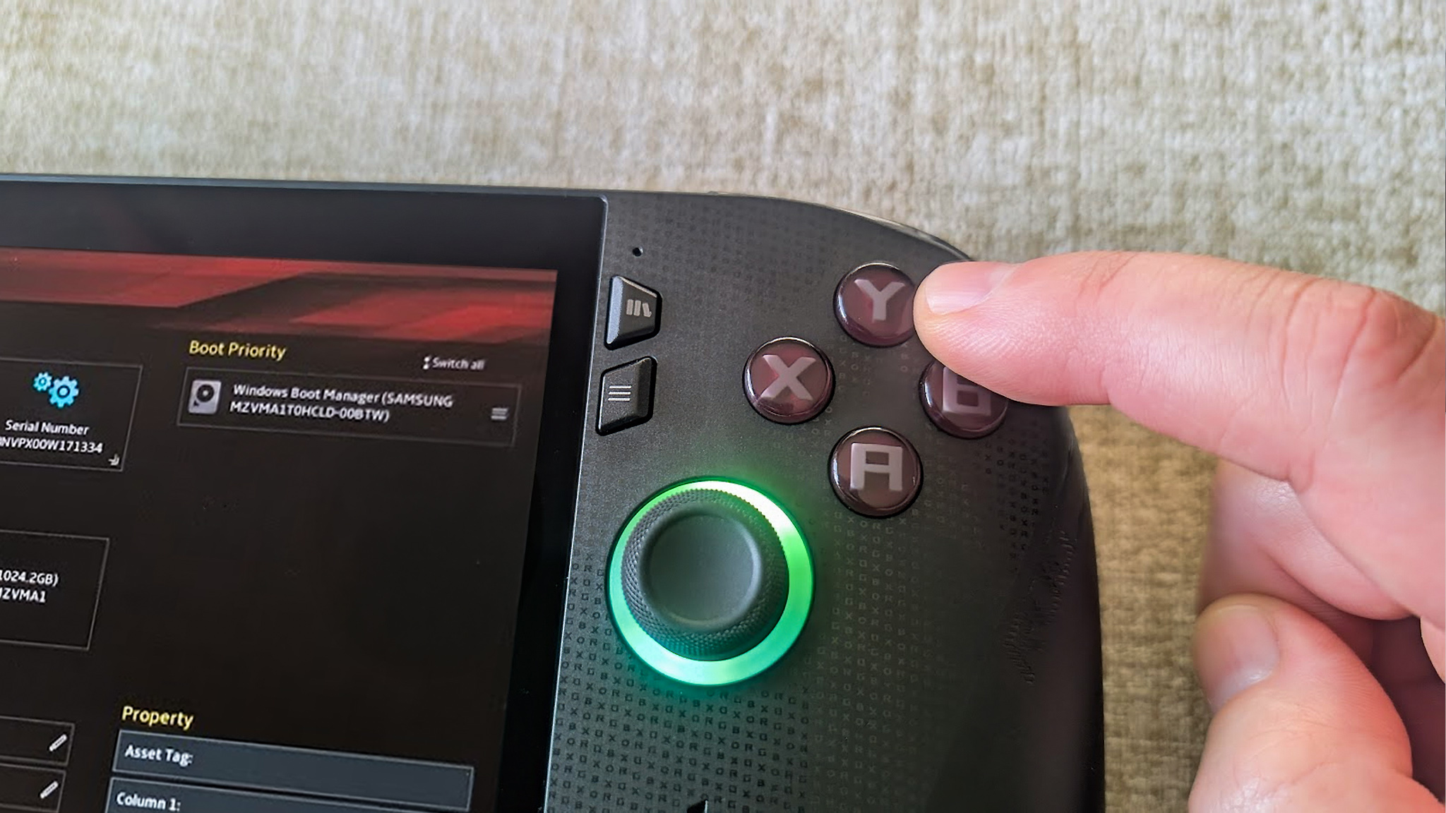 Xbox Ally X показывает BIOS, а палец нажимает кнопку Y на портативной консоли.