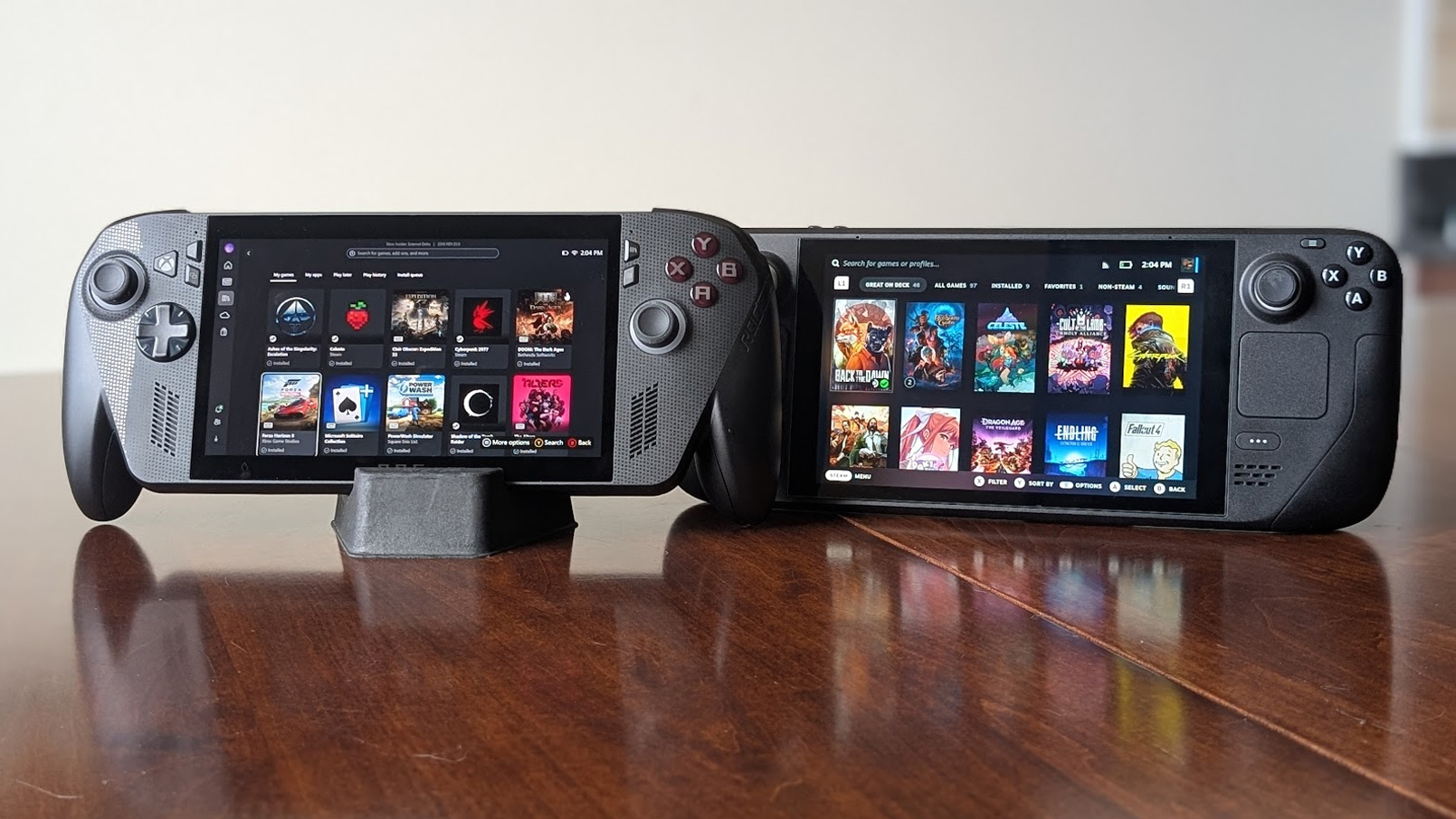Xbox Ally X отображает полный экран Xbox, а Steam Deck показывает интерфейс SteamOS, лежа на столе.