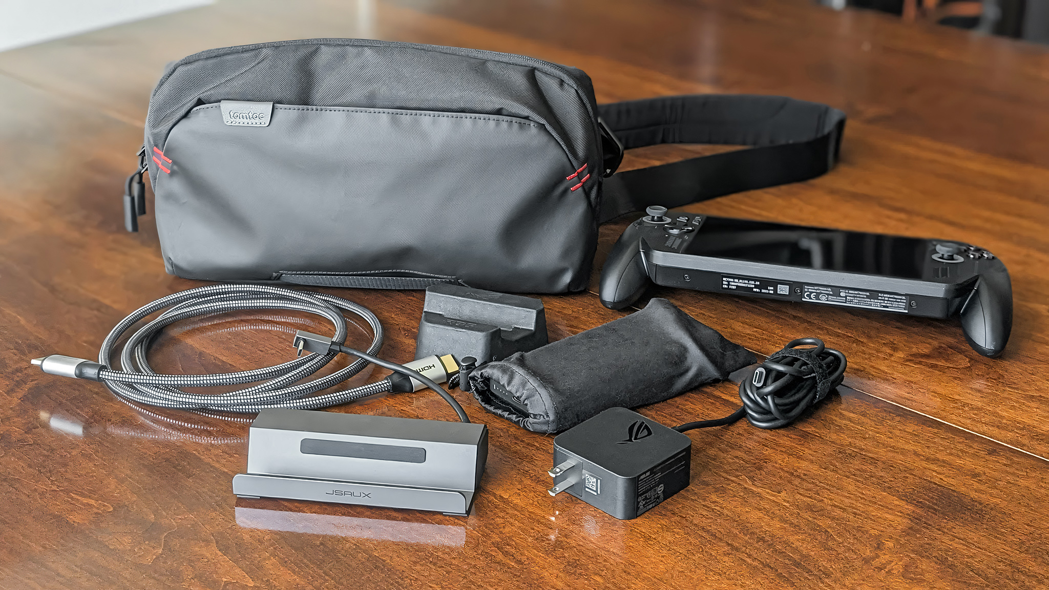 Дорожная сумка Tomtoc Arccos G-47 рядом с Xbox Ally X, кабелем HDMi, док-станцией, портативным аккумулятором, зарядным устройством Xbox Ally X и картонной подставкой Xbox Ally X.
