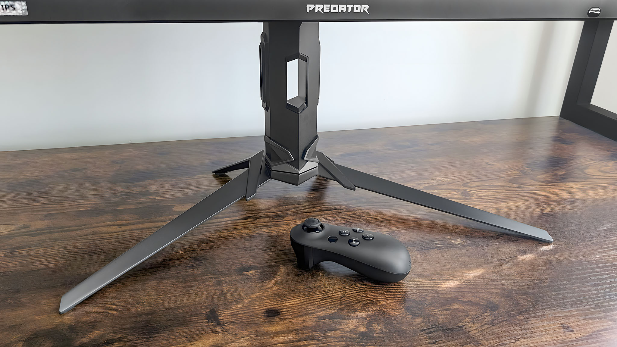 A closeup of the Acer Predator XB273K's base and remote as they sit on a desk.