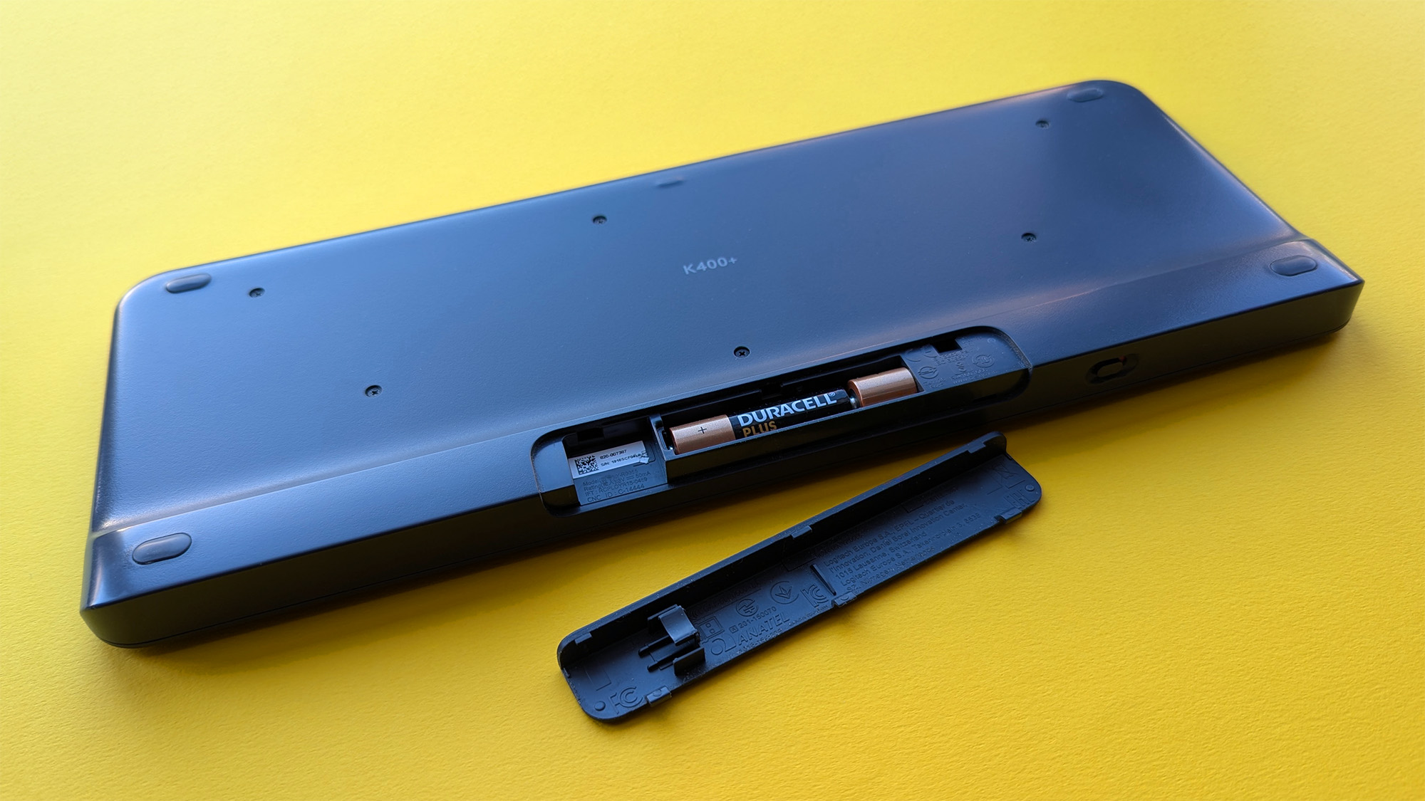 Closeup of Logitech K400 Plus wireless keyboard showing open battery compartment and Duracell batteries