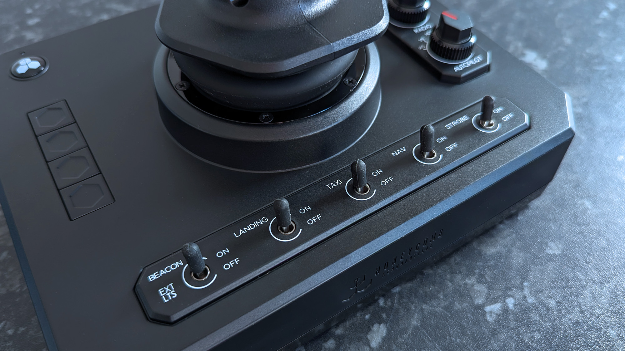 Крупный план переключателей на джойстике Honeycomb Aeronautical Foxtrot Aviation Stick на столе с мраморным узором