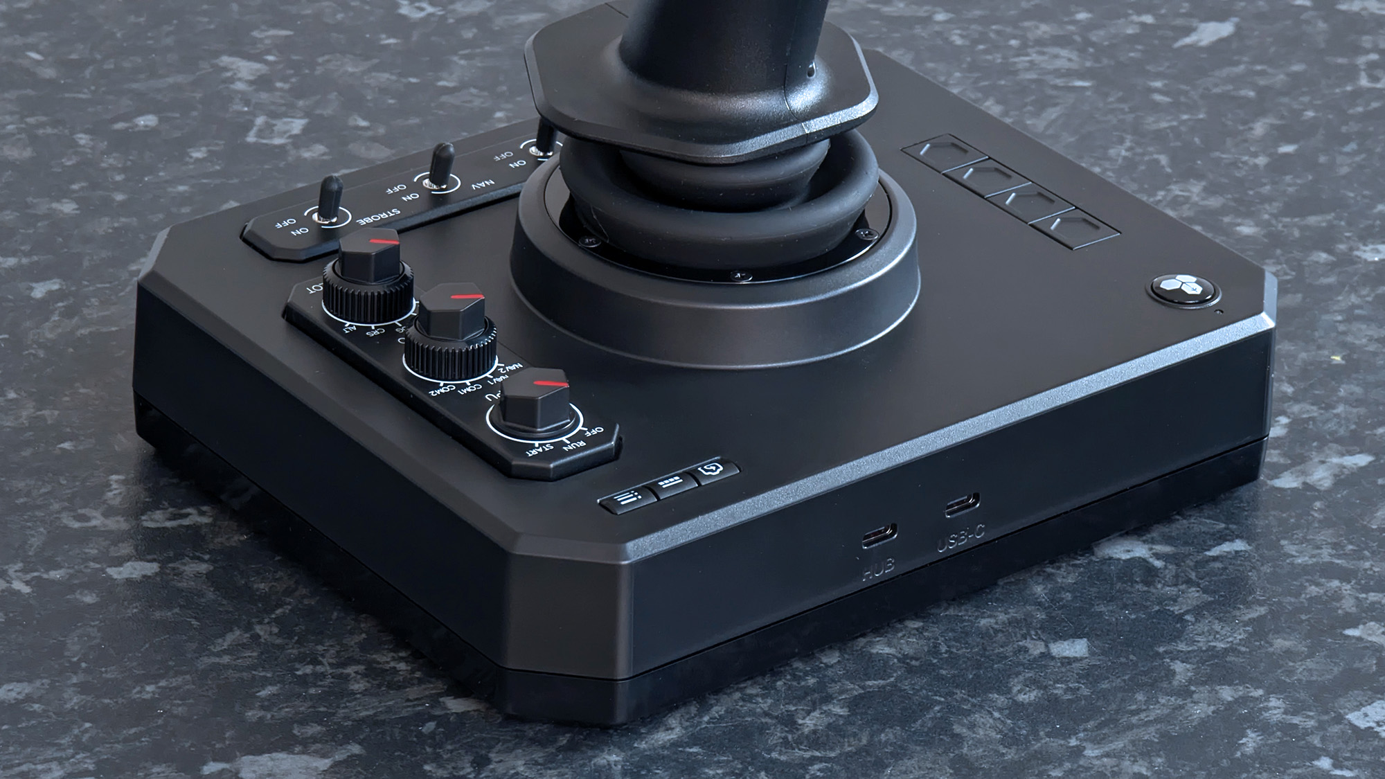 Задние порты USB-C рядом с переключателями на джойстике Honeycomb Aeronautical Foxtrot Aviation Stick на столе с мраморным узором