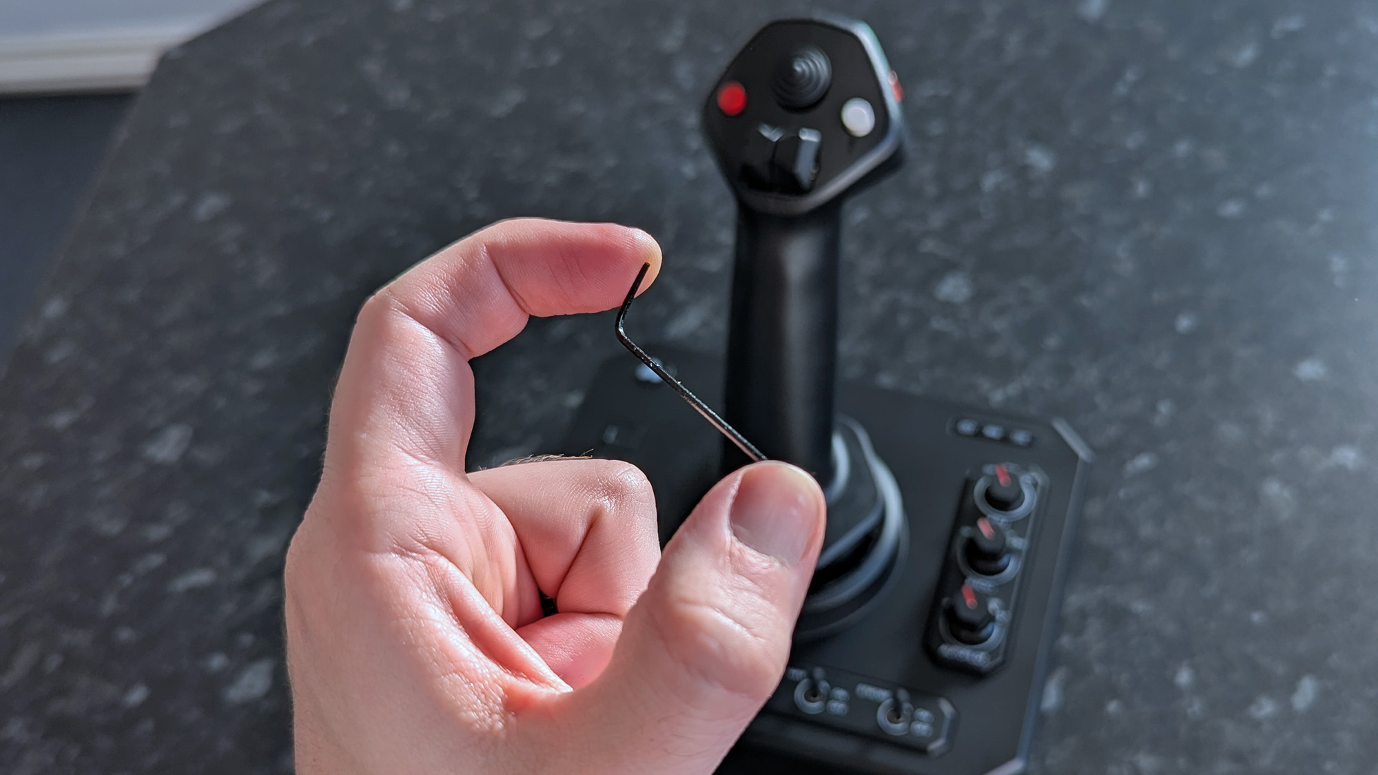 Маленький шестигранный ключ перед джойстиком Honeycomb Aeronautical Foxtrot Aviation Stick на столе с мраморным узором