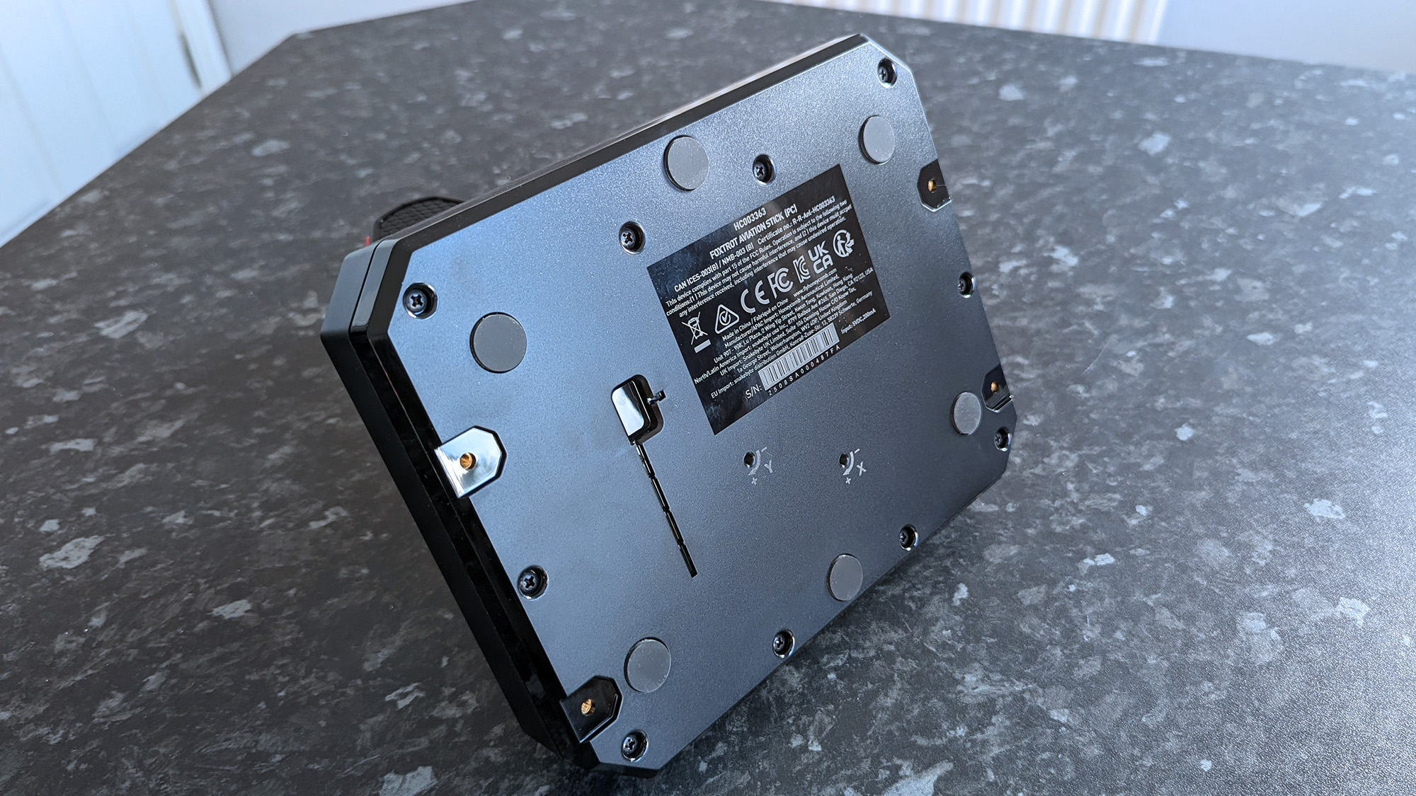 Вид снизу на джойстик Honeycomb Aeronautical Foxtrot Aviation Stick на столе с мраморным узором