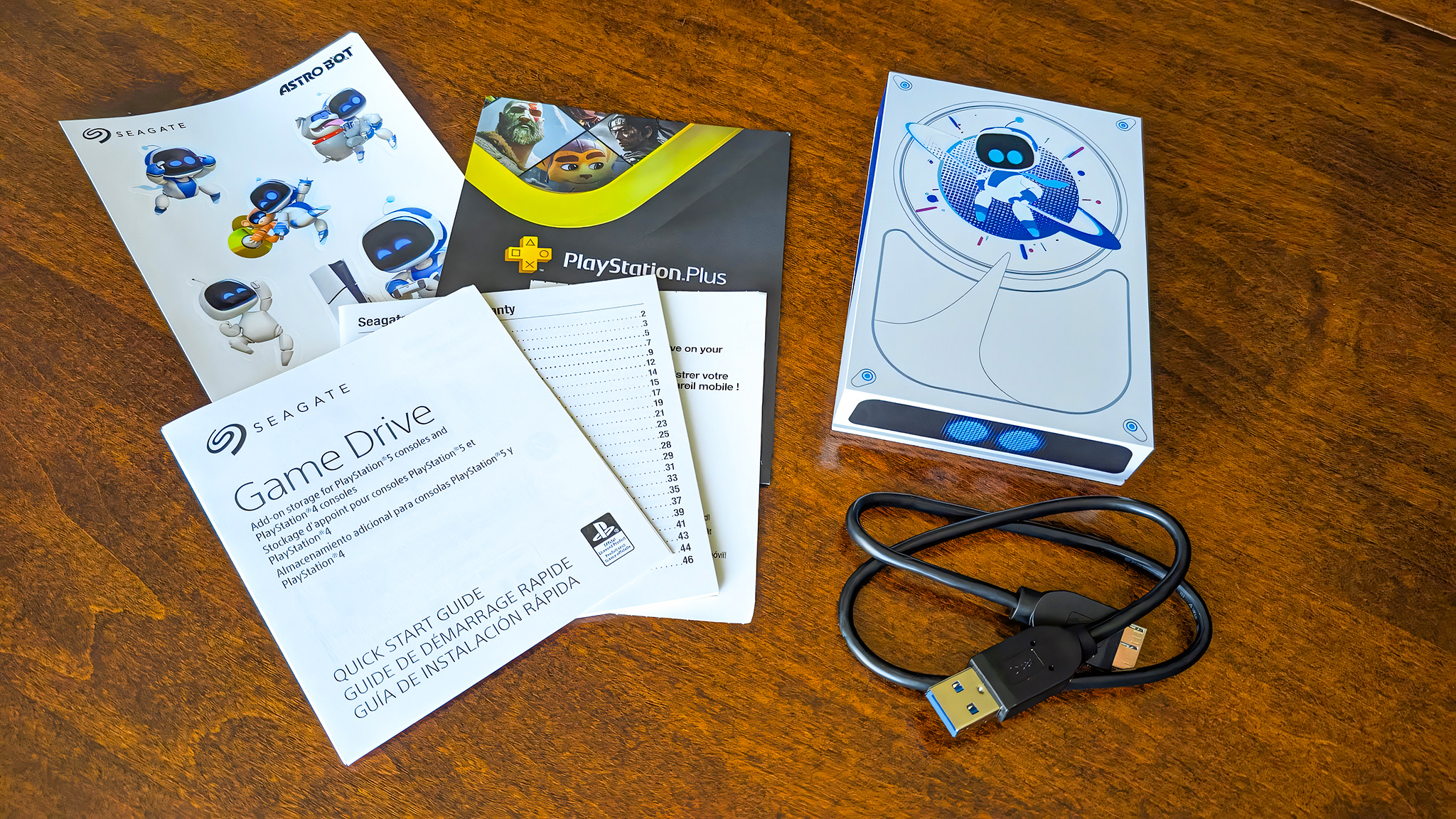 Seagate Astro Bot Limited Edition Game Drive with its included USB 3.0 cable, manuals, PlayStation trial, and Astro Bot stickers.