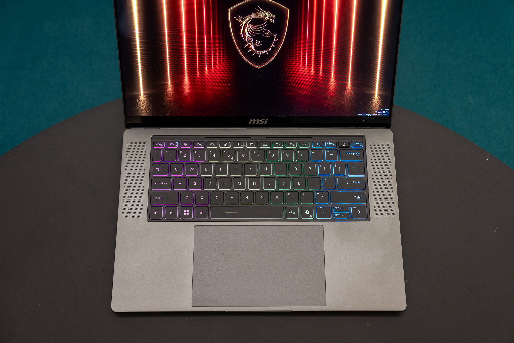 MSI Stealth 16 AI Plus laptop on a table, illuminated from behind.